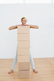 Smiling woman moving in new house with a stack of boxes