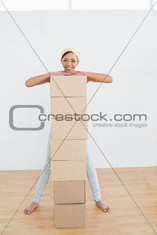 Smiling woman moving in new house with a stack of boxes