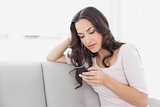 Woman text messaging on sofa at home