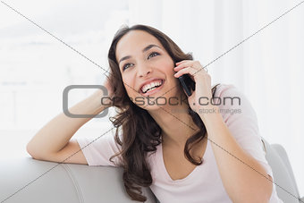 Relaxed happy woman using cellphone on sofa at home