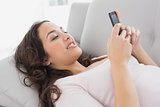 Smiling young woman text messaging on sofa at home