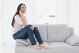 Relaxed young woman using cellphone on sofa at home