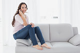 Relaxed young woman using cellphone on sofa at home