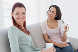 Young female friends with coffee cups sitting at home