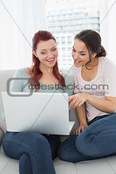 Relaxed young female friends using laptop at home