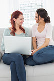 Relaxed female friends using laptop at home