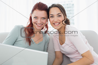Portrait of relaxed friends using laptop at home