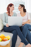 Relaxed female friends using laptop at home