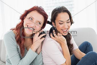 Friends listening music through headphones together at home