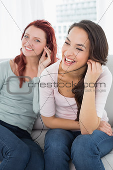 Friends listening music through earphones together at home