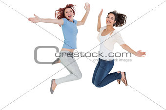 Two cheerful young female friends jumping