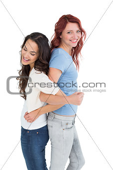 Young women standing back to back with interlocked hands