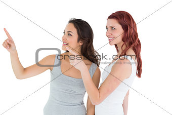 Two young female friends pointing away