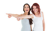 Two cheerful female friends pointing away