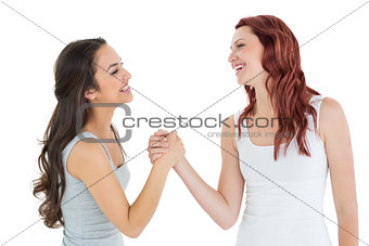Two cheerful young female friends arm wrestling