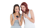 Shocked young female friends looking at mobile phone