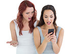 Shocked female friends looking at mobile phone