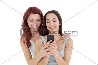 Smiling female friends looking at mobile phone