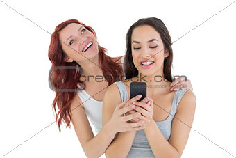 Smiling young female friends with mobile phone