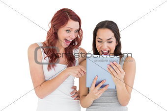 Shocked young female friends looking at digital tablet
