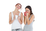 Two smiling young female friends drinking coffee