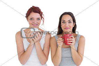 Two smiling young female friends with coffee cups