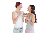 Cheerful young female friends eating pastry together