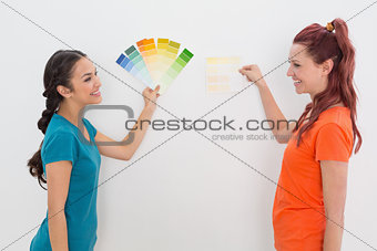 Cheerful friends choosing color for painting a room
