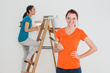 Female friends with paint brushes and ladder