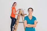 Female friends with paint brushes and ladder