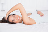 Smiling pretty young woman lying in bed