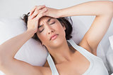 Sleepy woman suffering from headache in bed