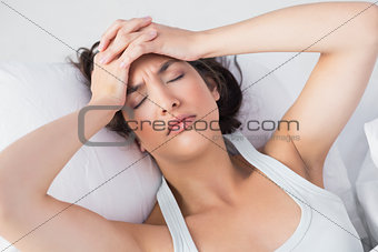 Sleepy woman suffering from headache in bed