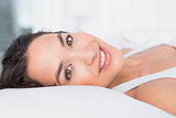 Close-up of a smiling pretty woman lying in bed