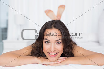 Portrait of a smiling brunette lying in bed