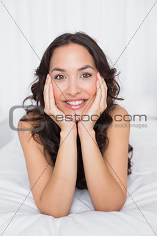Close-up of a smiling brunette lying in bed