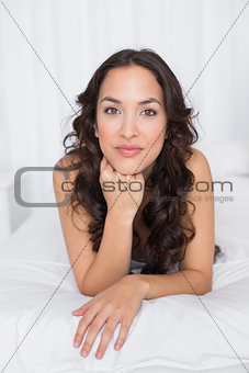 Portrait of a pretty brunette lying in bed