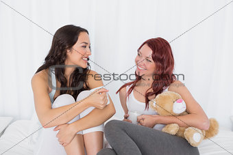 Relaxed female friends chatting over coffee in bed