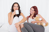 Portrait of female friends with coffee cups in bed