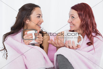 Female friends with coffee cups in bed