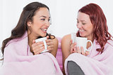 Happy female friends with coffee cups in bed