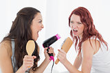 Female friends singing into hairbrush