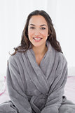 Portrait of a young female in bathrobe sitting on bed
