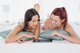 Female friends using digital table in bed
