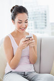 Relaxed woman text messaging on sofa at home