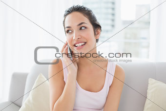 Young woman using cellphone on sofa in living room