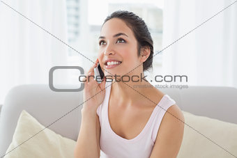 Woman using cellphone on sofa in living room