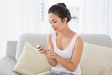 Relaxed young woman text messaging on sofa at home