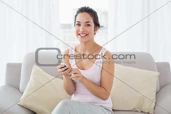 Portrait of a smiling woman text messaging on sofa