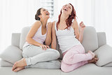 Beautiful young female friends laughing in living room